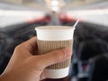 Male hand holding hot drink in aircraft cabin. steam from hot coffee.
