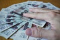 Male hand holding its fingers on the circle created of Russian currency Russian Rubles on the wooden table