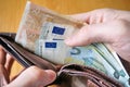 Male hand holding a leather wallet and withdrawing European currency (Euro, EUR) Royalty Free Stock Photo