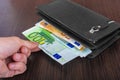 Male hand holding a leather wallet and withdrawing European currency Euro EUR Royalty Free Stock Photo