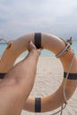 Male hand holding a life preserver. In the background sand, sea and sky Royalty Free Stock Photo