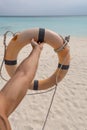 Male hand holding a life preserver. In the background sand, sea and sky Royalty Free Stock Photo