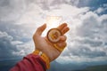 Male hand is holding a magnetic compass on the background of sky with clouds. The concept of traveling and finding your