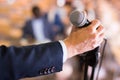 Male hand holding microphone at conference hall Royalty Free Stock Photo