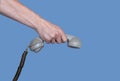 Male hand holding an old gray plastic telephone receiver on blue background. Close up remote handset from a retro rotary Royalty Free Stock Photo