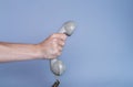 Male hand holding an old gray plastic telephone receiver on blue background. Close up remote handset from a retro rotary Royalty Free Stock Photo