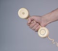 Male hand holding an old plastic telephone receiver on gray background. Close up remote handset from a retro rotary home Royalty Free Stock Photo