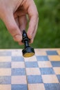 Male hand holding one chess piece of black bishop over empty chessboard