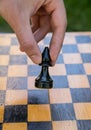 Male hand holding one chess piece of black bishop over empty chessboard