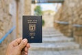 Male hand holds an Israel passport on the old narrow street background Royalty Free Stock Photo