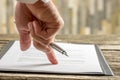 Male hand holding a pen pointing to a line at the end of a contract Royalty Free Stock Photo