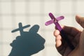 Male hand holding purple wooden cross with shadow. Christianity, faith, holy week and lent season.