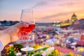 Male hand holding red wine glass against the aerial cityscape view of Rome at sunset with St Peter Cathedral in Vatican Royalty Free Stock Photo