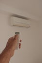 Male hand holding remote control air conditioner on blurred background living room. Space for text Royalty Free Stock Photo