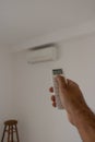 Male hand holding remote control air conditioner on blurred background living room. Space for text Royalty Free Stock Photo