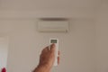 Male hand holding remote control air conditioner on blurred background living room. Space for text Royalty Free Stock Photo