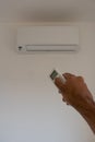 Male hand holding remote control air conditioner on blurred background living room. Space for text Royalty Free Stock Photo