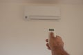 Male hand holding remote control air conditioner on blurred background living room. Space for text Royalty Free Stock Photo