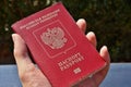 Male hand holding a Russian passport with captions Passport and Russian Federation in Cyrillic alphabet