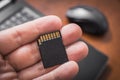 Male Hand Holding An SD Card With Laptop Computer And Mouse In Background, Extent Disk Space Concept Royalty Free Stock Photo