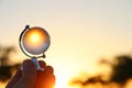 male hand holding small crystal globe in front of setting sun Royalty Free Stock Photo