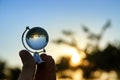 male hand holding small crystal globe in front of sunset Royalty Free Stock Photo