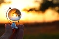 male hand holding small crystal globe in front of sunset Royalty Free Stock Photo