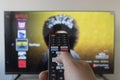 A male hand holding a smart tv remote control with blurred netflix interface Royalty Free Stock Photo