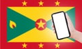 Male hand holding smartphone with blank on screen, on background of blurred flag of Grenada. Close-up view.
