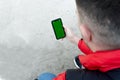 Male hand holding smartphone with green display for your content, man`s hand using cellphone with empty screen
