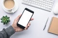 Male hand holding smartphone on office desk table