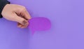 Male hand holding a speech balloon shape card on a violet background