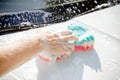 Male hand holding sponge for washing white car.dirty auto.Man worker washing windshield with sponge on a car wash.Manual car wash Royalty Free Stock Photo