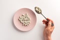 Male hand holding spoon with pills. Plate with pills.