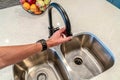 Male hand holding spout of black curved faucet of stainless steel two bowl sink Royalty Free Stock Photo
