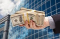 Male Hand Holding Stack of Cash with Corporate Building Royalty Free Stock Photo