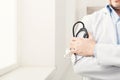 Male hand holding stethoscope in bright room closeup Royalty Free Stock Photo