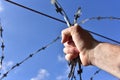 Male hand holding on to the barbed wire against the blue sky. The concept of not freedom as exclusion and desire for freedom Royalty Free Stock Photo