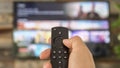 Male hand holding the TV remote control and changing TV channels Royalty Free Stock Photo