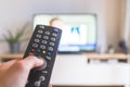 Male hand is holding TV remote control, streaming on a smart TV Royalty Free Stock Photo