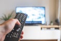 Male hand is holding TV remote control, streaming on a smart TV Royalty Free Stock Photo