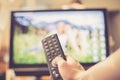 Male hand is holding TV remote control, streaming on a smart TV Royalty Free Stock Photo