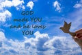 Male hand holding wooden bird on cloud sky background. Words `God made you and he loves you` The development of the imagination, Royalty Free Stock Photo