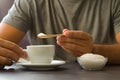 Male hand holding wooden spoon with sugar over cup of coffee or tea. Stop sugar. Campaign against diabetes, obesity, dental caries