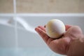 Male hand holding yellow colored bath bomb over hot water bath filling up. Royalty Free Stock Photo