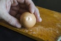 A male hand holds a boiled chicken egg in his shell against the chopping board Royalty Free Stock Photo