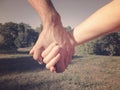 A male hand holds a female hand against a background of nature. Couple on a walk holding hands, the concept of a relationship of