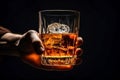Male hand holds glass of whiskey on black background, space for text Royalty Free Stock Photo