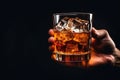 Male hand holds glass of whiskey on black background, space for text Royalty Free Stock Photo