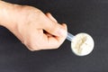 Male hand holds a measuring spoon with protein on black background top view Royalty Free Stock Photo